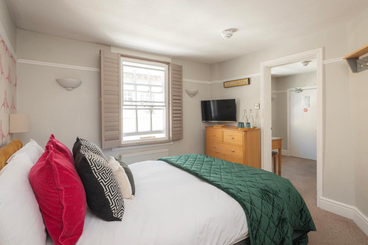 a bedroom with a bed with red and green pillows at Harington's Boutique Hotel in Bath